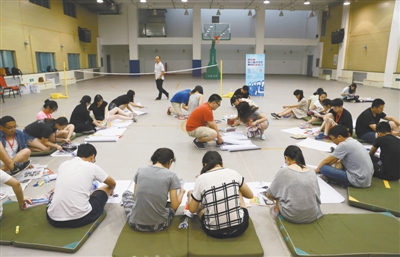 2015年7月14日，在北京一師附小地下體育館內(nèi)，2015新京報第八屆大學(xué)生名企實習(xí)學(xué)員在參加實習(xí)培訓(xùn)，在老師的指引下，通過裁剪雜志上的圖片，拼組自己的海報。